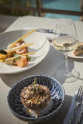 a table with two plates of food and a glass of wine at Hôtel La Plage 5 étoiles La Grande Motte in La Grande-Motte