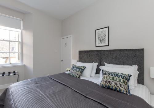 une chambre blanche avec un grand lit avec des oreillers dans l'établissement West Bow Apartment, à Édimbourg