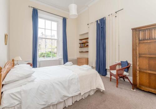 ein Schlafzimmer mit einem großen weißen Bett und einem Stuhl in der Unterkunft Melville Street Apartment in Edinburgh