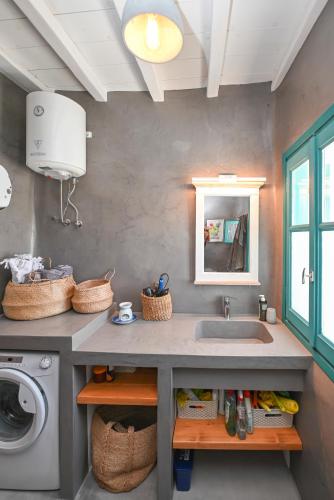 a bathroom with a sink and a washing machine at Tinos Traditional Patio House in Arnados