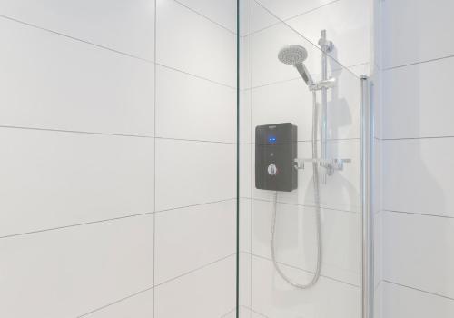 a shower with a shower head on a glass door at High Street Apartment in Edinburgh