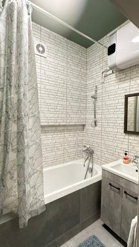 a bathroom with a bath tub and a sink at DOWNTOWN APPARTMENTS in Karagandy