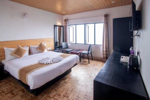 Cette chambre comprend un grand lit et un bureau. dans l'établissement Cherrywood Suites & Spa, à Darjeeling