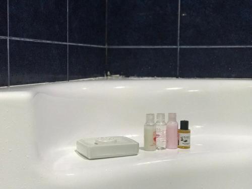 a white bath tub with bottles of cosmetics on it at Elena's room in Batumi