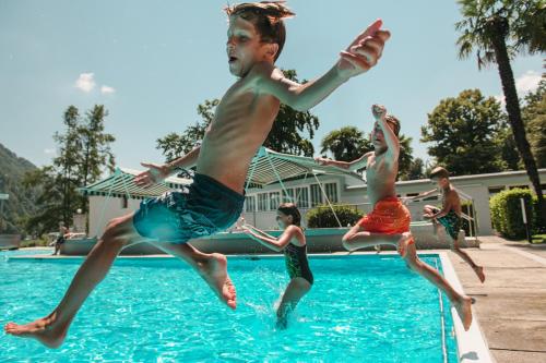 a group of people jumping into a swimming pool at Centro Magliaso in Magliaso