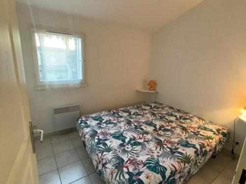 une chambre avec un lit avec un couvre-lit fleuri dans l'établissement Charmant Pavillon avec Terrasse, Piscine et Parking, Proche Plage et Commerces - 6 pers. - FR-1-701-32, à Valras-Plage