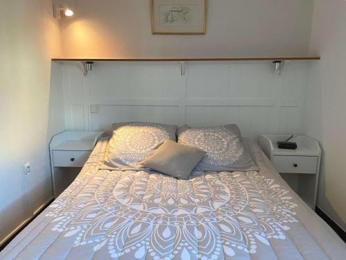 - un lit avec un couvre-lit blanc et des oreillers dans l'établissement Appartement T2 avec loggia et internet à deux pas de l'étang de Thau à Balaruc-les-Bains - FR-1-553-217, à Balaruc-les-Bains