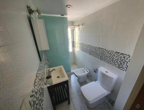 une salle de bain blanche avec toilettes et lavabo dans l'établissement ÀYRES PAMPA I PB, à Las Gaviotas