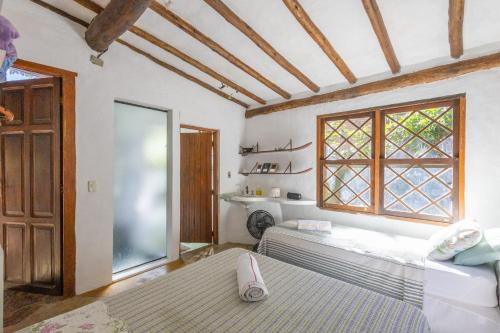 two beds in a room with a window at Casa Atelie Bangue in Ilhabela