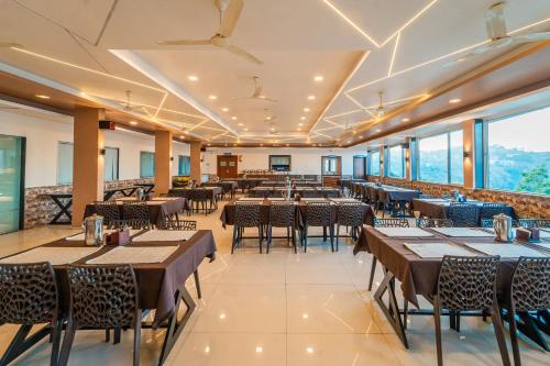 a restaurant with tables and chairs and large windows at Treebo Kaizen, 3 Kms From Paragliding in Panchgani