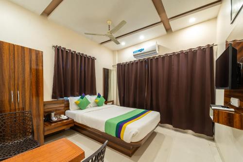 a bedroom with a bed and a flat screen tv at Treebo Kaizen, 3 Kms From Paragliding in Panchgani