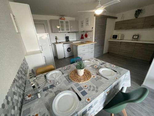 une cuisine avec une table avec des assiettes dessus dans l'établissement Petit Cocon a deux pas de la mer, à Saint-Cyprien