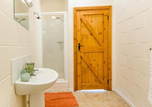 a bathroom with a sink and a wooden door at The Corn Bin in Sedlescombe