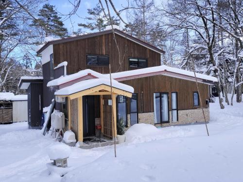 a house covered in snow in front at Nestle Inn Hakuba in Hakuba