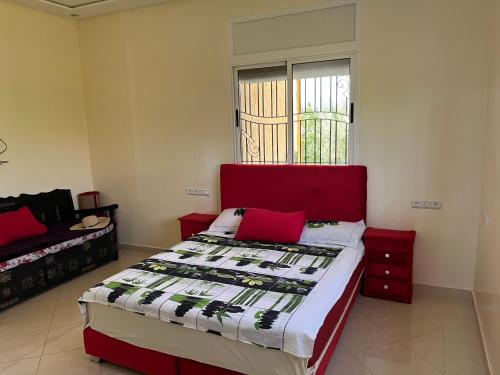 sypialnia z łóżkiem z czerwonym zagłówkiem i oknem w obiekcie Maison Dar Zarka w mieście Aghmat