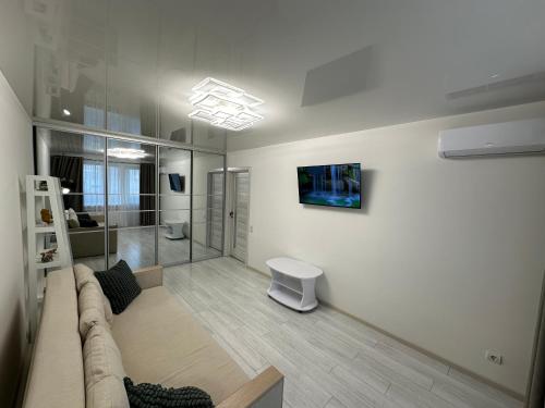 ein Wohnzimmer mit einem Sofa und einem TV an der Wand in der Unterkunft Bilius Apartment in Winnyzja