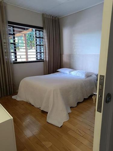 Schlafzimmer mit einem weißen Bett und einem Fenster in der Unterkunft SHOW RURAL 2024- casa com ar e piscina in Cascavel