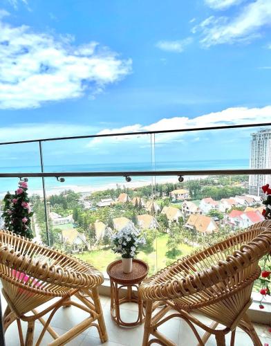 a balcony with two chairs and a table with flowers at The Song Luxury Vung Tau Apartment - QUỲNH's Homestay in Vung Tau