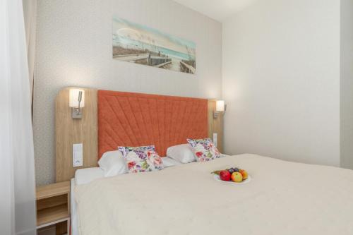 a bedroom with a bed with a bowl of fruit on it at Bel Mare Modern Apartment with Balcony by Renters in Międzyzdroje