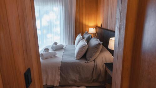 Un dormitorio con una cama con almohadas y una ventana. en RentUp - Experimenta la belleza de San Martin de los Andes, en San Martín de los Andes