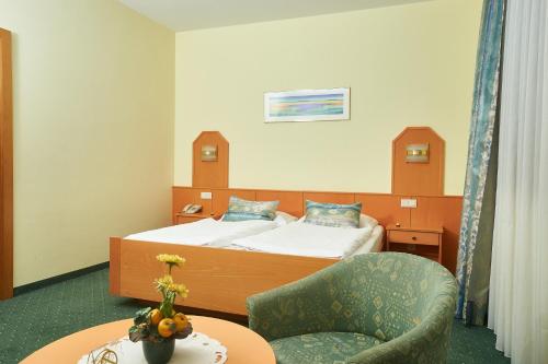 um quarto de hotel com uma cama, uma cadeira e uma mesa em Pension Sprinzl em Schwechat