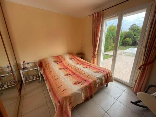 un lit dans une chambre avec une grande fenêtre dans l'établissement Villa St Cyprien piscine privée vélos wifi, à Saint-Cyprien