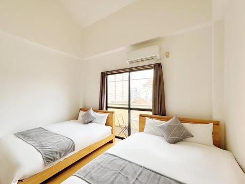 two beds in a room with a window at 千間川-緑橋 in Osaka