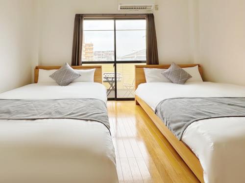 two beds in a room with a window at 千間川-緑橋 in Osaka