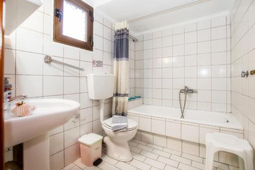 a bathroom with a toilet and a tub and a sink at Studios Anagnostou in Skala Marion