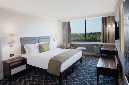 a hotel room with a bed and a desk and a window at Riverside Sun in Vanderbijlpark