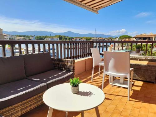 a patio with a couch and tables on a balcony at Spacieux Studio 3pers vue marina a St Cyprien in Saint-Cyprien