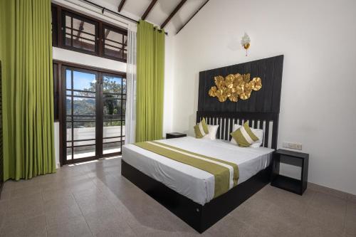 a bedroom with a large bed with green curtains at Indra Manel Family Holiday Resort Kandy in Kandy
