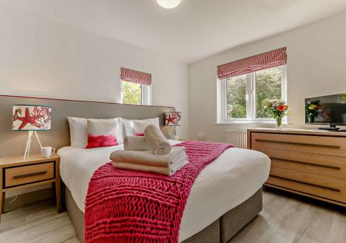 a bedroom with a large bed with a red blanket at Sennen - St Ives in Carbis Bay