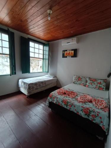 a bedroom with two beds and two windows at Pousada do Guerreiro in Cachoeira