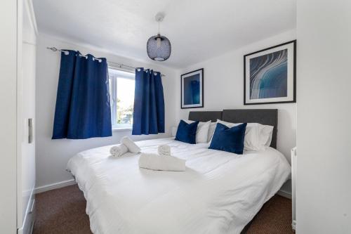 a bedroom with a large white bed with blue curtains at Mead Court Estate Apartment in Egham By Rent Firmly Short Lets Serviced Accommodation With Free On-Site Parking in Egham