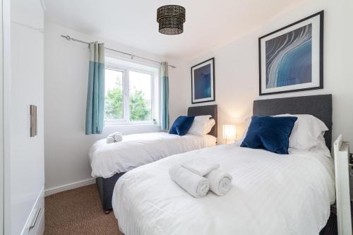 two beds in a room with two windows at Mead Court Estate Apartment in Egham By Rent Firmly Short Lets Serviced Accommodation With Free On-Site Parking in Egham