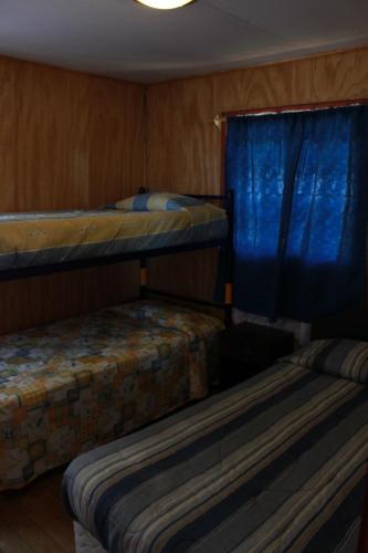 2 literas en una habitación con cortinas azules en Cabañas y Agroturismo RanchoJyC, en Teodoro Schmidt