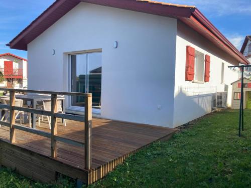 une terrasse en bois à côté d'une maison blanche dans l'établissement Maison 2 chambres, à Cambo-les-Bains