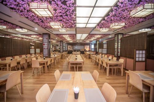 un restaurante con mesas, sillas y flores púrpuras en el techo en Vé tắm Yoko Onsen Quang Hanh - khung giờ sáng, en Cẩm Phả