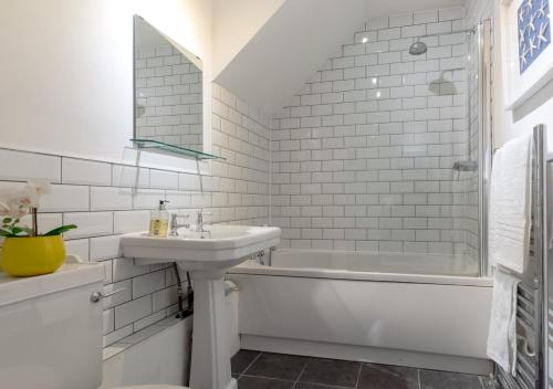 uma casa de banho branca com um lavatório e uma banheira e um lavatório em Fern Cottage - Whitstable em Whitstable
