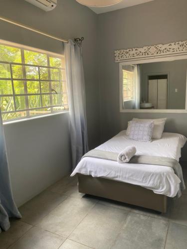 a bedroom with a bed with a mirror and a window at Backstage Theatre Room in Tsumeb