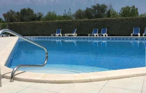 - une piscine avec des chaises bleues et un billard dans l'établissement Appart de standing avec piscine, à Saint-Cyprien