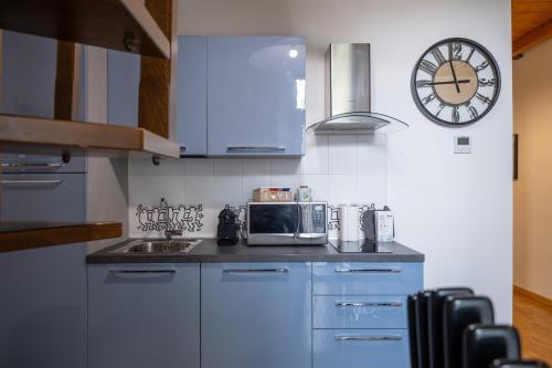 a kitchen with a microwave and a clock on the wall at Lungarno Buozzi 7 Apartments in Pisa