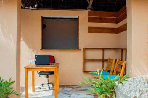 a room with a desk and a television on a wall at Cappadocia Hotel in Nungwi