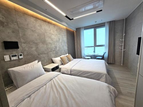 Habitación de hotel con 2 camas y ventana en Elliy's Room, en Busan