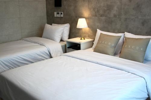 two beds in a room with a lamp on a table at 라비앙즈-Raviens-Elliy's Room in Busan