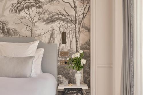 a bedroom with a painting of trees and a vase with flowers at Airelles Château de la Messardière in Saint-Tropez
