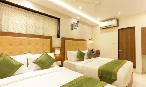 ムンバイにあるNew Amber Palace Hotelのベッド2台と窓が備わるホテルルームです。