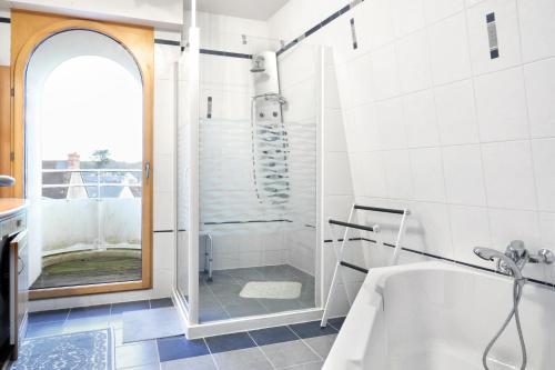 La salle de bains blanche est pourvue d'une douche et d'une baignoire. dans l'établissement L'Abri du Repos - Appt vue sur le port, à Barneville-Carteret