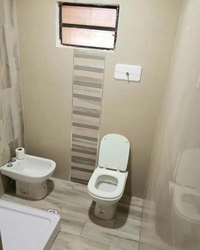 a white bathroom with a toilet and a sink at Villa Narcisa in Purmamarca